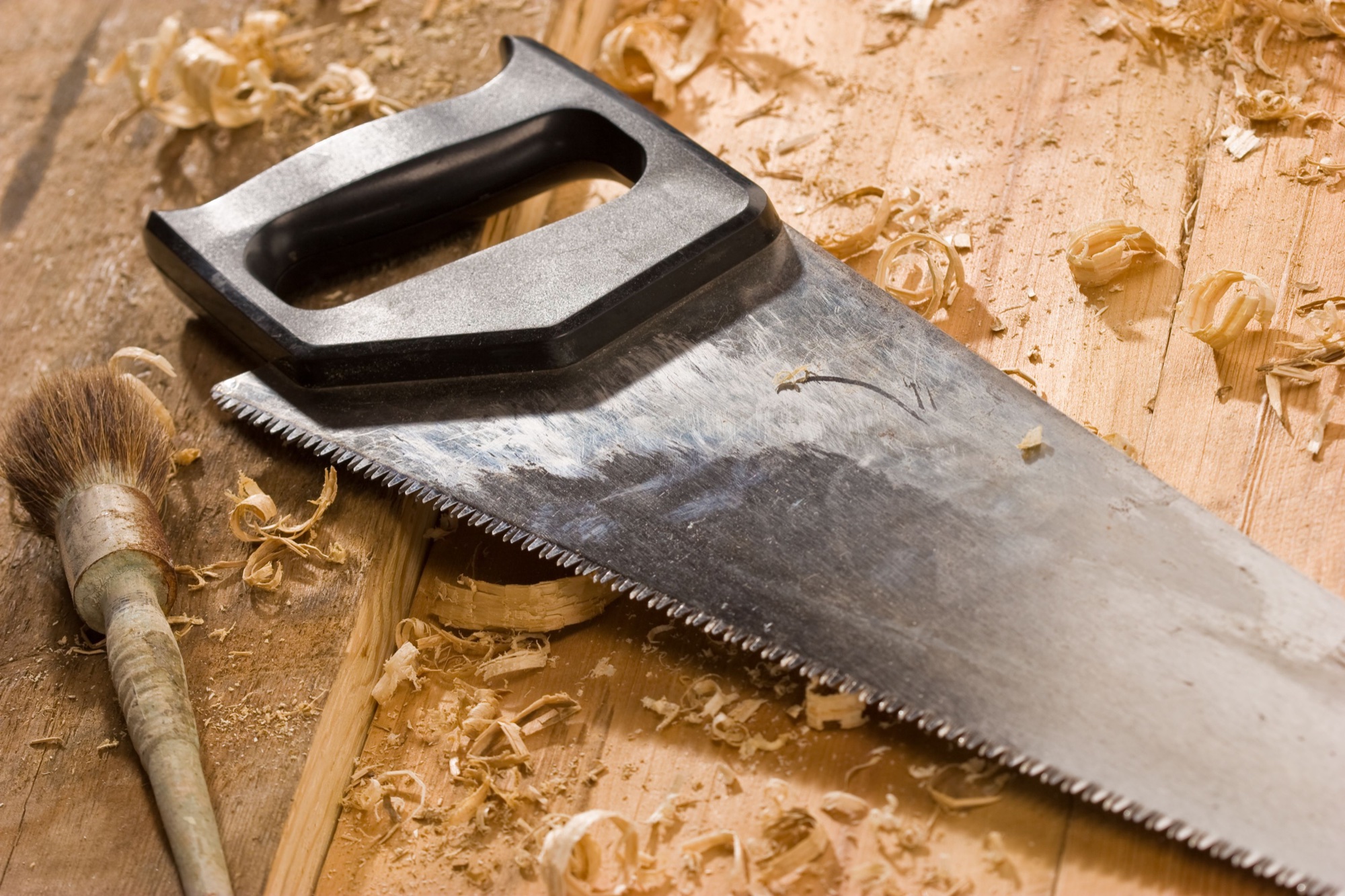 A handsaw and brush on a timber workbench